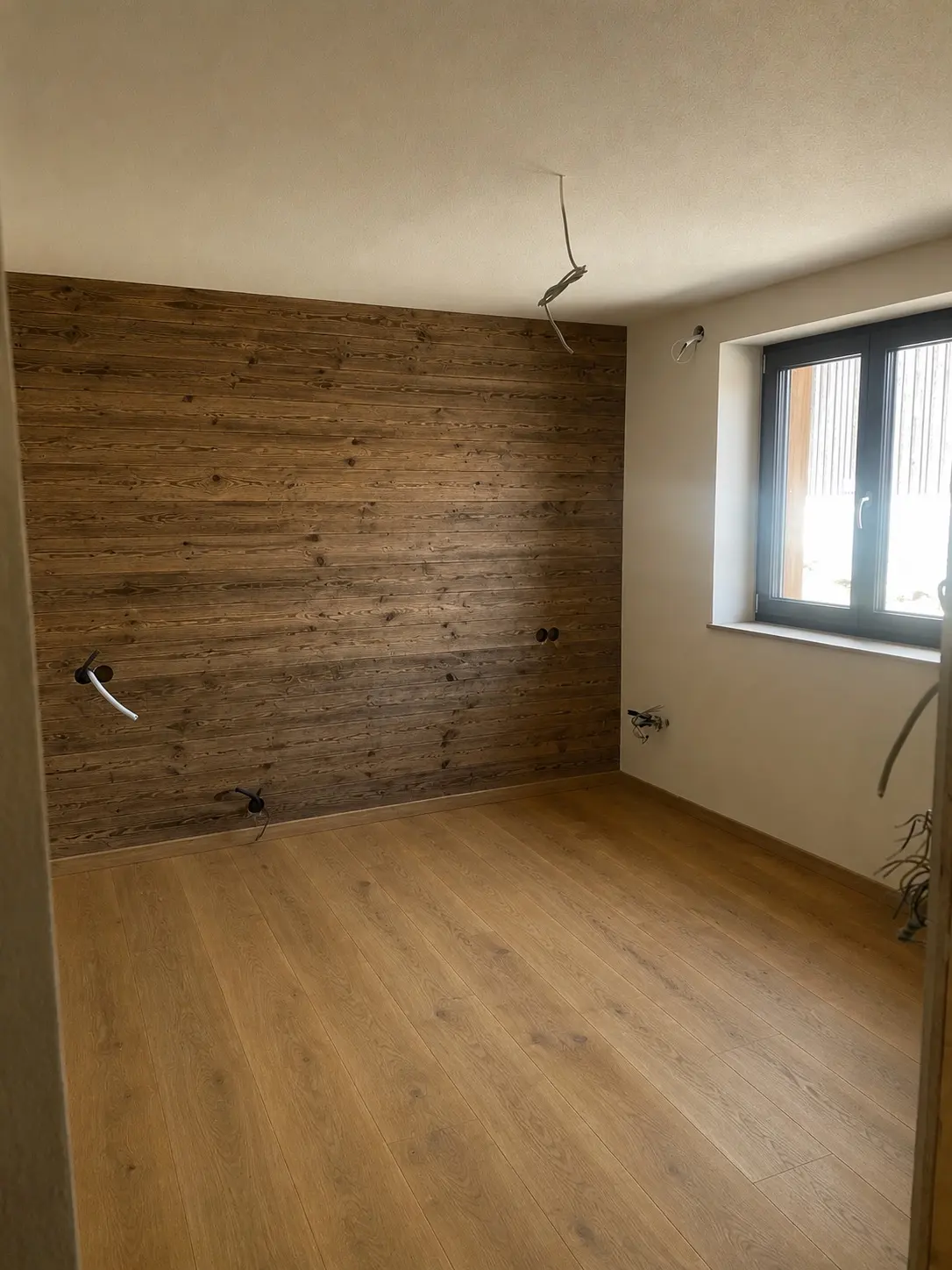Zimmer mit Altholz-Wandverkleidung und Holzboden