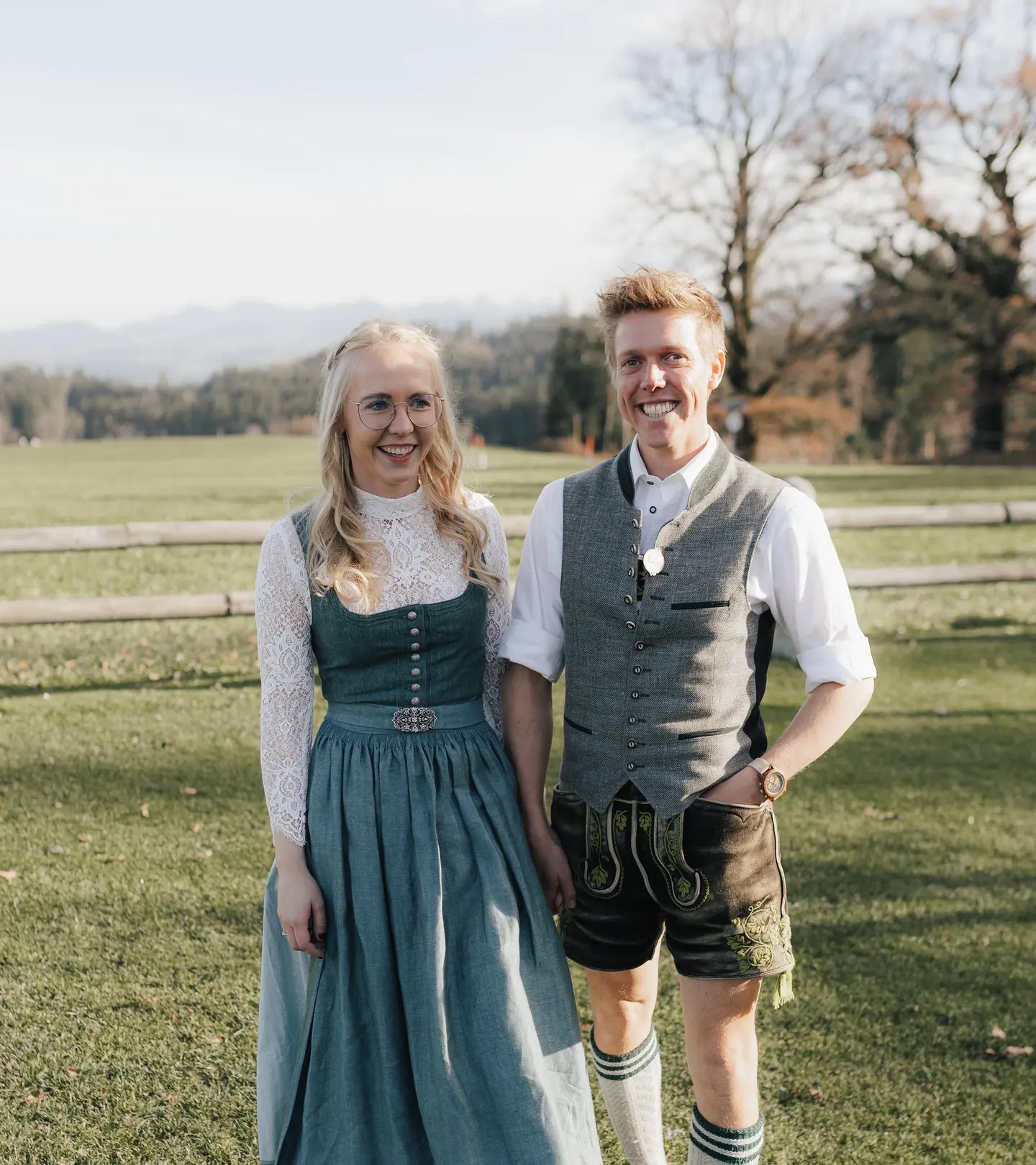 Svea und Markus in Tracht auf der Wiese vor den Bergen